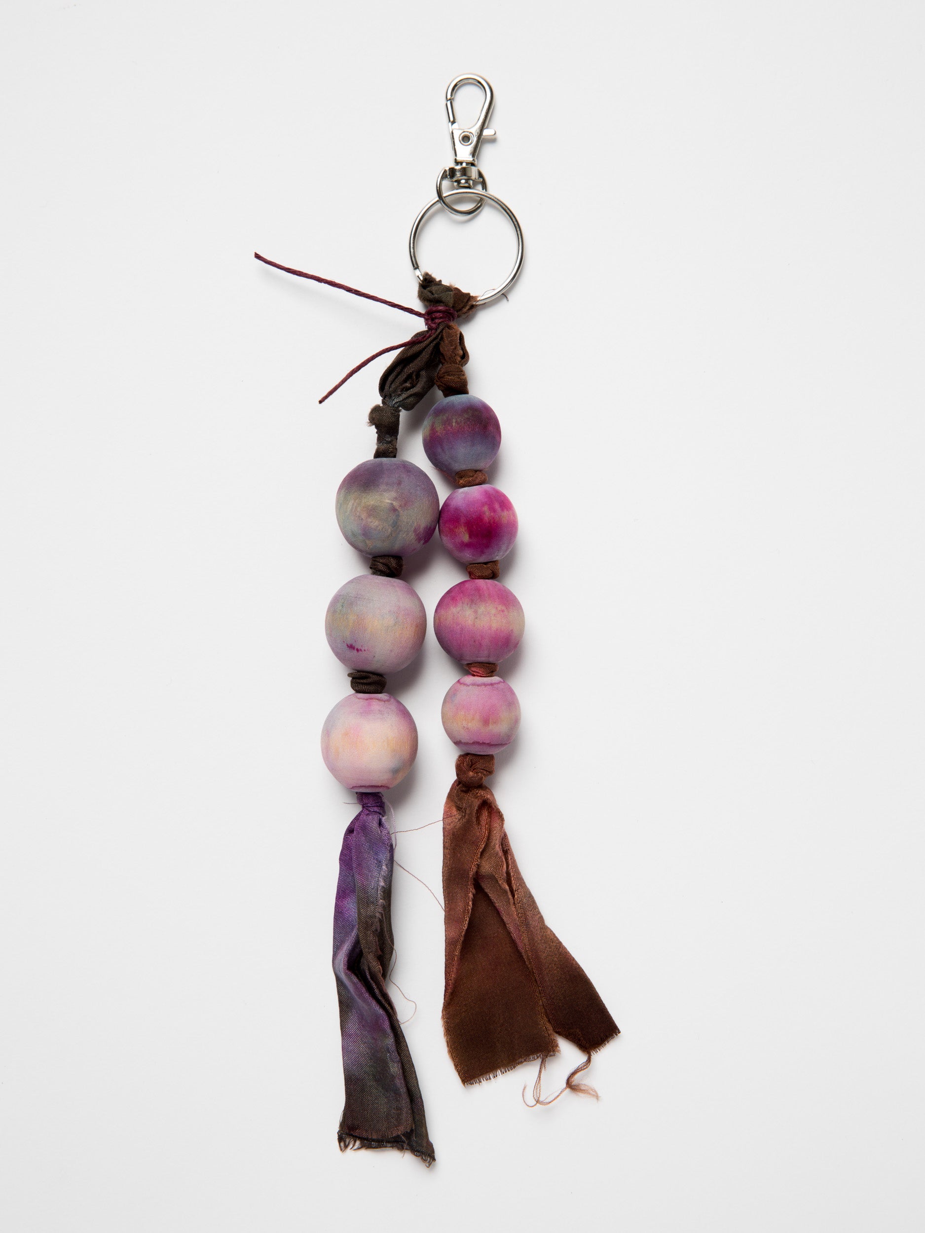 Handmade bag charm made with wooden beads and silk ribbons on a white background