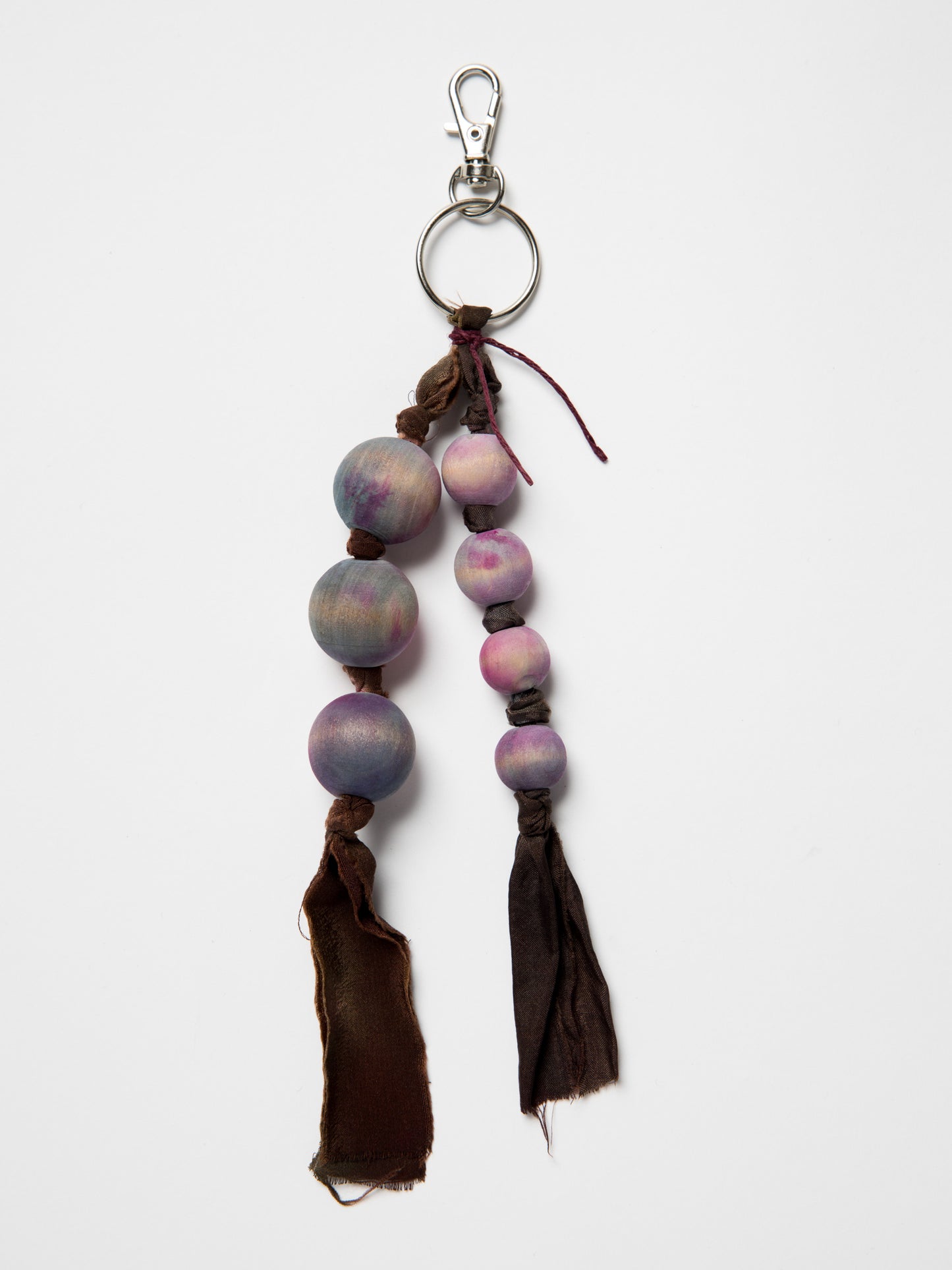 Handmade bag charm made with wooden beads and silk ribbons on a white background